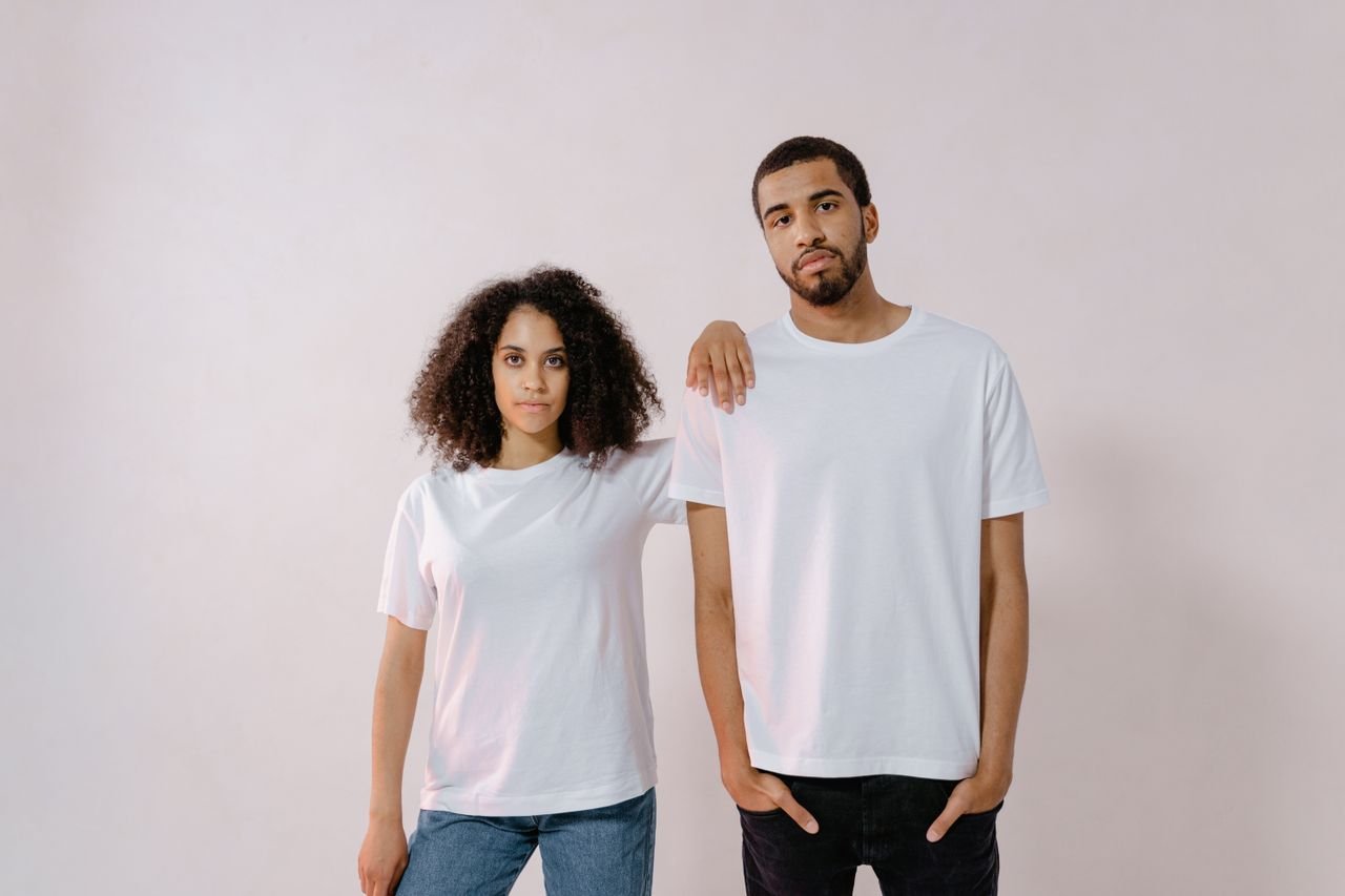 A young man and woman in casual white T-shirts, standing confidently for a fashion photoshoot.